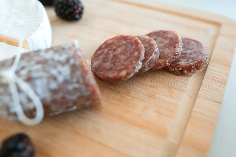 Saucisson sec entamé et tranché sur une planche en bois